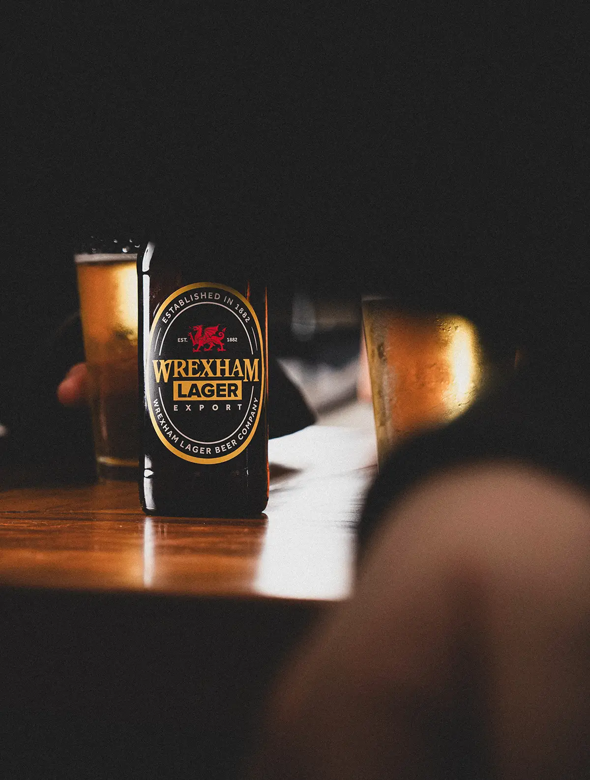 Person holding a bottle of Wrexham Export at a bar